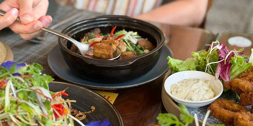 Die Hand einer Frau, die in Vietnam gerade mit einem Löffel nach Essen greift