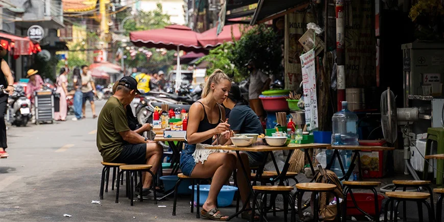Frau sitzt an einem Straßenimbiss in Vietnam