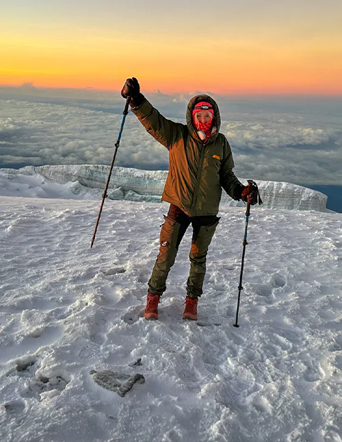 Cat von TourCompass steht bei Sonnenaufgang auf dem Gipfel des Kilimandscharo