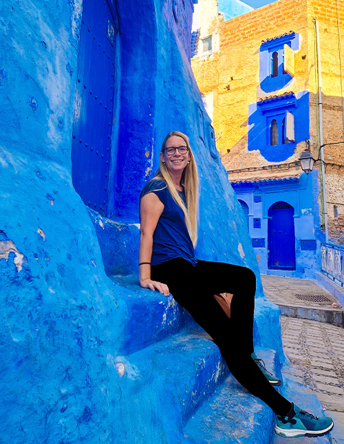 Eine Frau sitzt auf den Stufen in der blauen Stadt Chefchaouen in Marokko