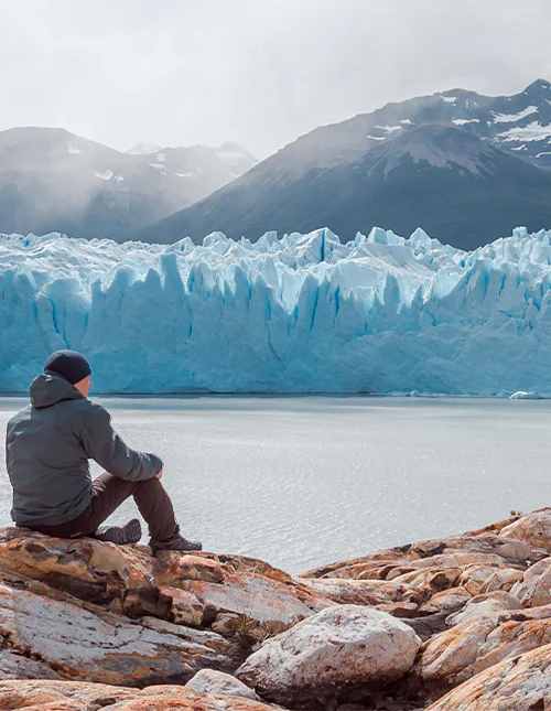 Mann sitzt vor dem Perito-Moreno-Gletscher im Nationalpark Los Glaciares