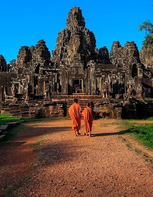Mönche inmitten der uralten Steingesichter des Bayon-Tempels, Angkor, Kambodscha