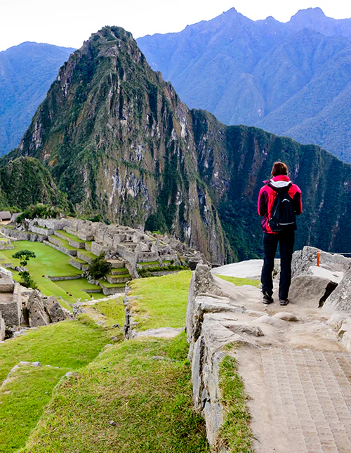 Eine Person steht und blickt hinab auf Machu Picchu