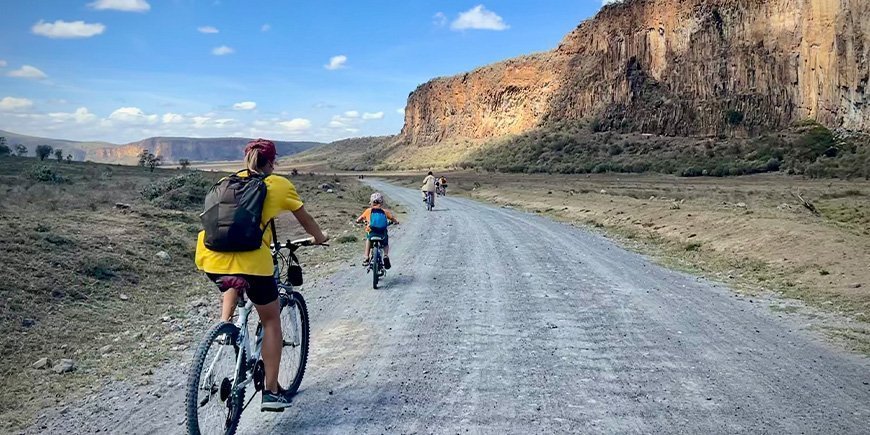 Frau und Familie beim Radfahren im Hells Gate National Park in Kenia.