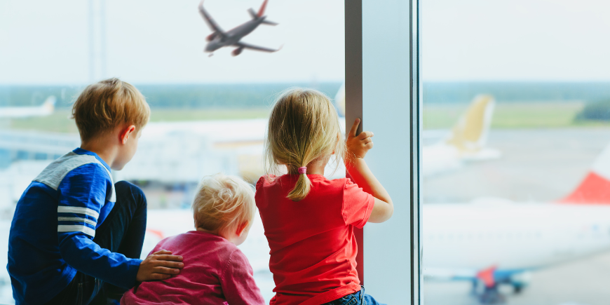 Drei Kinder warten am Flughafen