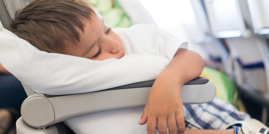 Junge schläft im Flugzeug mit einem Polster