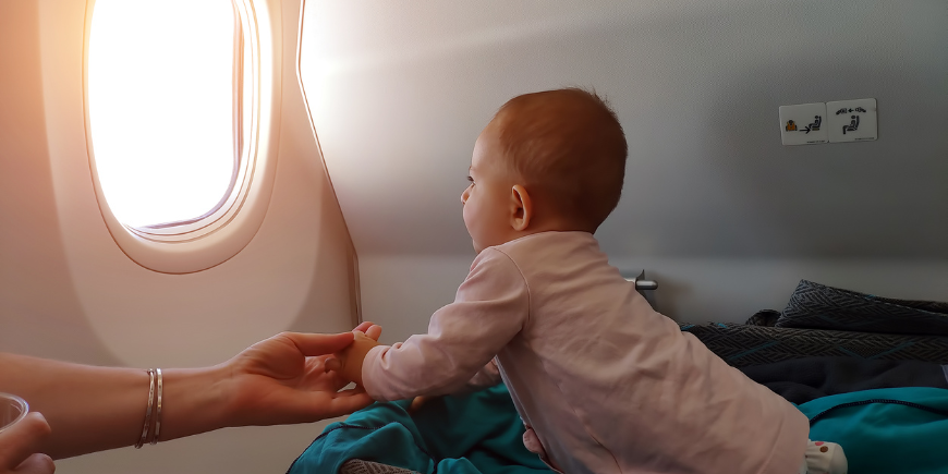 Kleines Baby schaut aus dem Flugzeugfenster