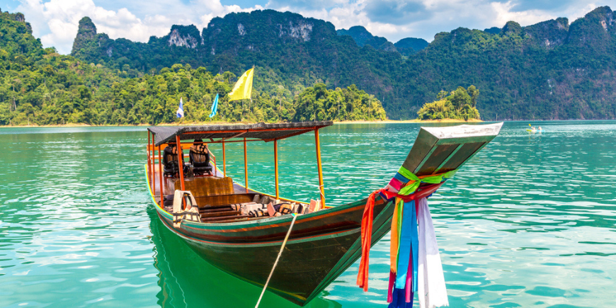 Traditionelles Langboot und wunderschöner Blick auf die Landschaft am Ratchaprapha-Staudamm im Nationalpark Khao Sok.