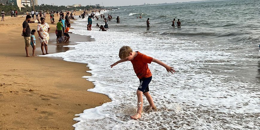 Junge geht am Wasser des goldenen Strandes von Sri Lanka