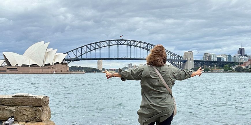 Beate steht vor dem Opernhaus und der Sydney Harbour Bridge in Australien