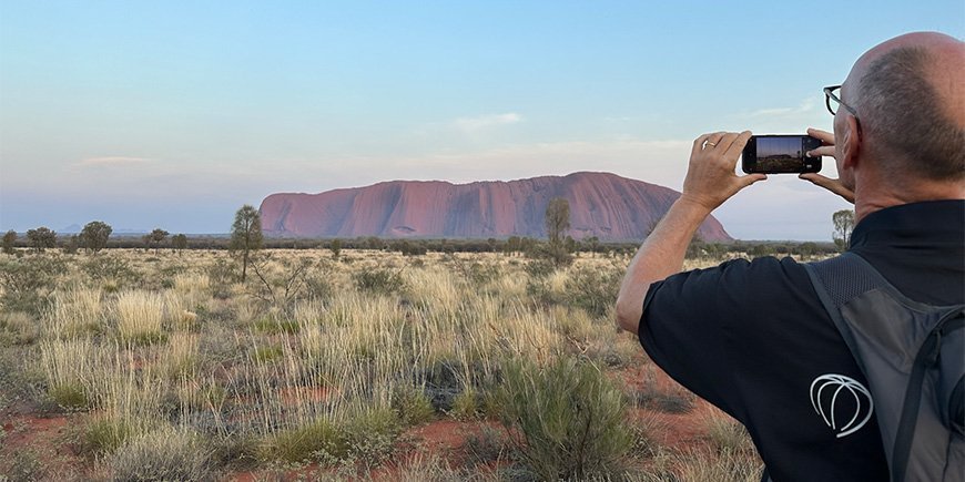 Ein Mann macht ein Foto vom Uluru in Australien