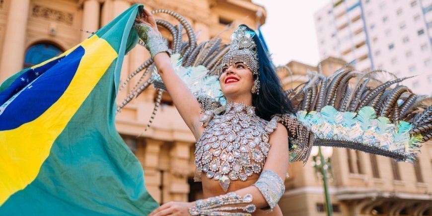 Brasilianische Frau in bunter Kleidung hält die brasilianische Flagge