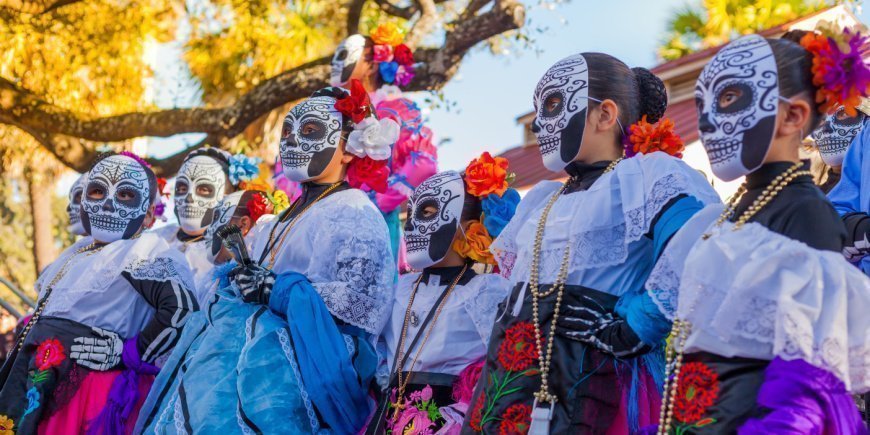 Frauen in bunten Kostümen mit geschmückten Schädeln am Tag der Toten in Mexiko