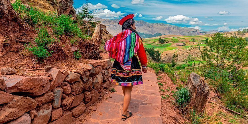 Indigene Frau geht im Oktober an einer Inka-Mauer in Cusco entlang