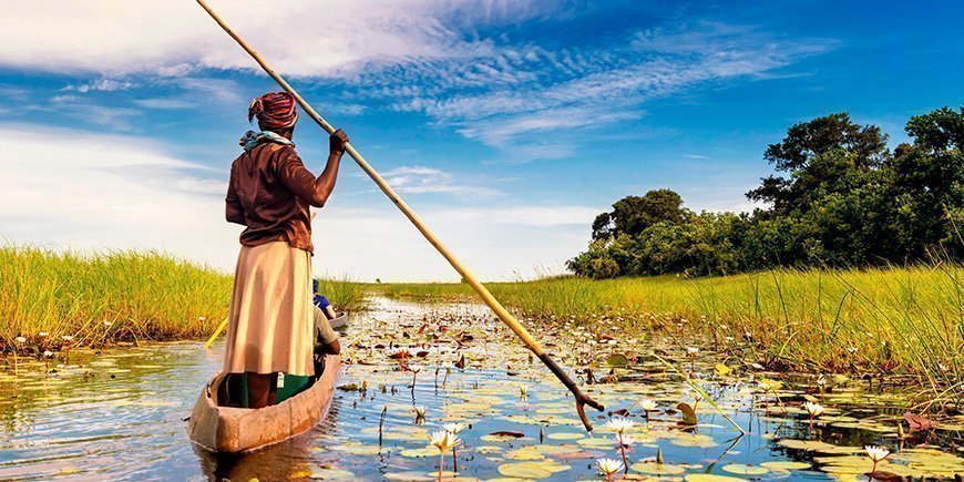 Frau beim Segeln in einem Boot im Okavango-Delta in Botswana