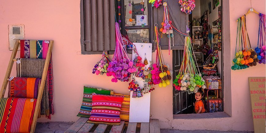 Kleiner lokaler Laden in Purmamarca, Argentinien, und ein Mädchen, das in der Tür sitzt.
