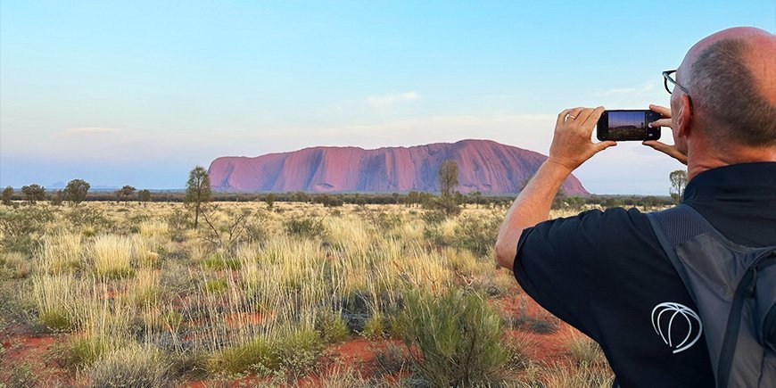Mann macht Handy-Foto von Uluru in Australien