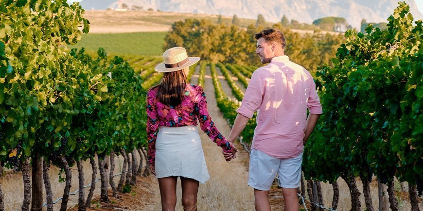 Frau und Mann halten Händchen in einem Weinberg in Südafrika