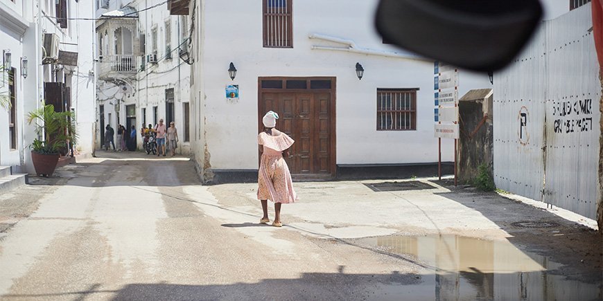 Frau im Kleid geht durch die Straßen von Stone Town