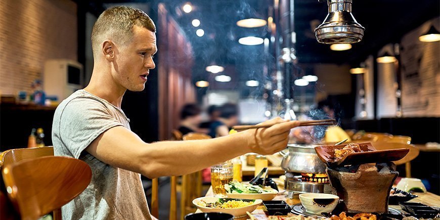 Mann isst mit Stäbchen in einem Restaurant in Vietnam