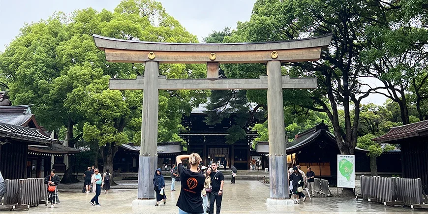 Frau fotografiert ein Paar unter einem Torii-Tor am Meiji-Schrein