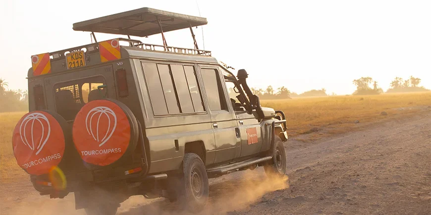 Jeep mit TourCompass-Logo fährt durch die Savanne in Kenia