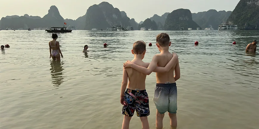 Zwei Jungen umarmen sich an einem Strand in der Halong-Bucht