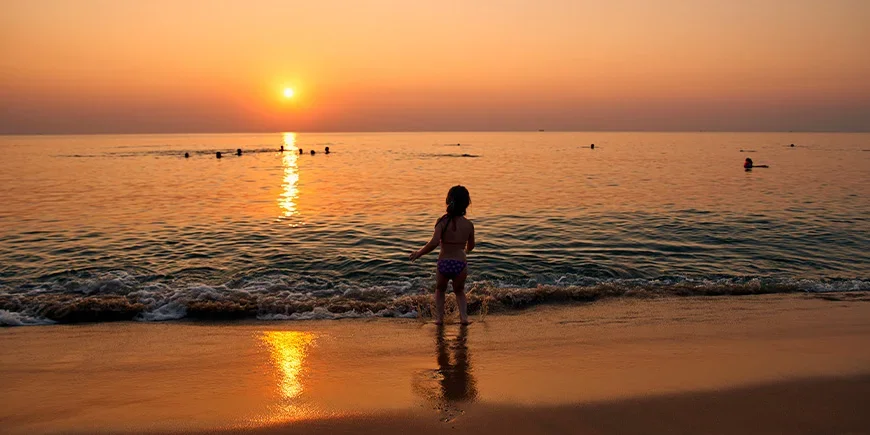 Mädchen spielt im Wasser bei Sonnenuntergang auf Phu Quoc