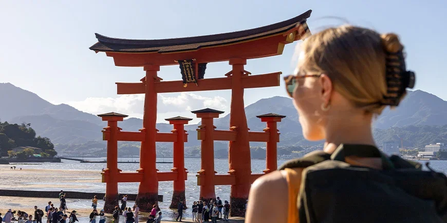 Frau blickt auf den roten Schrein auf der Insel Miyajima in Hiroshima
