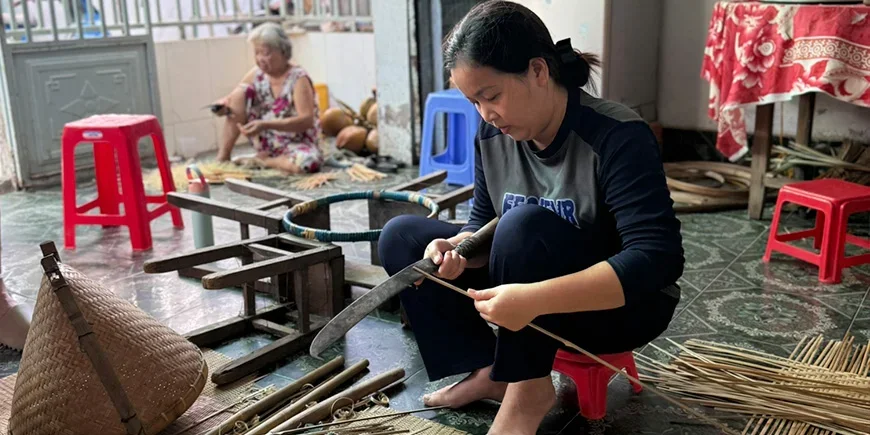 Vietnamesische Frau, die aus Kokosnüssen Souvenirs herstellt